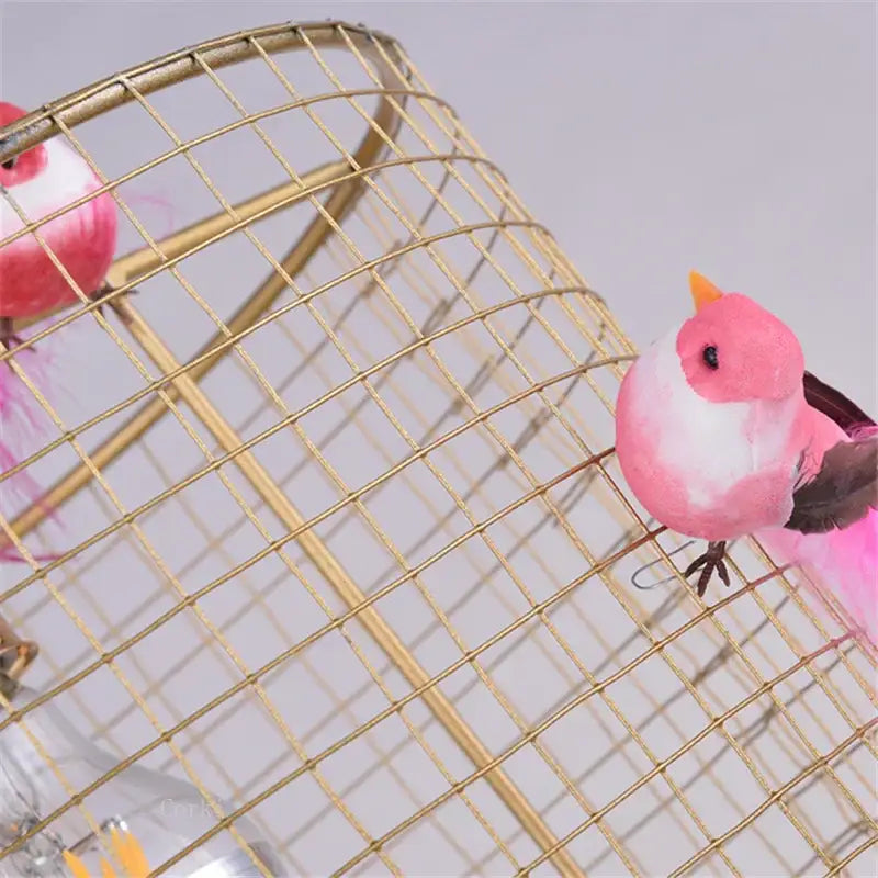 Pink and white decorative bird figurine with yellow beak perched on a gold wire nordic pendant lamp bird cage decorbites bird cage
