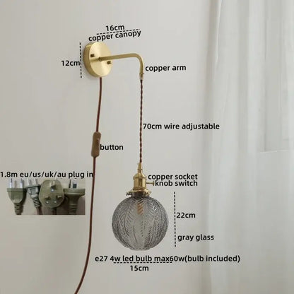 Vintage-style wall sconce lamp with brass-finished copper arm and gray etched glass globe on braided cord for bedroom