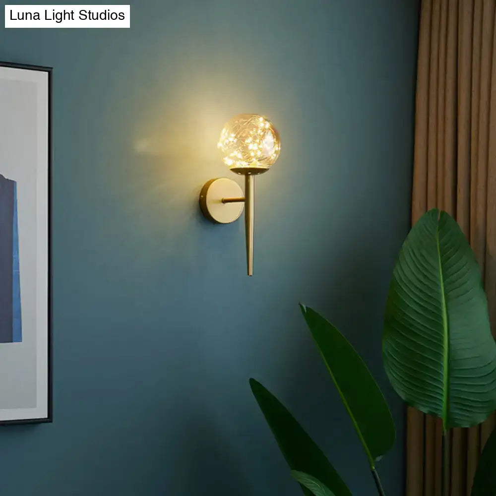 Nordic gold wall sconce featuring a gold-toned metal frame and spherical glass globe with warm LED bedroom fairy lights