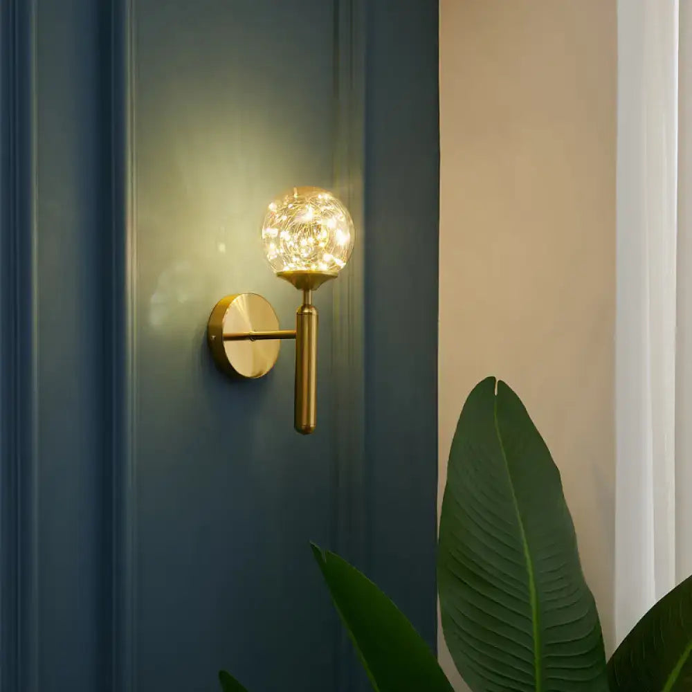 Nordic gold glass globe wall sconce with crackled spherical shade emitting warm light for bedroom use