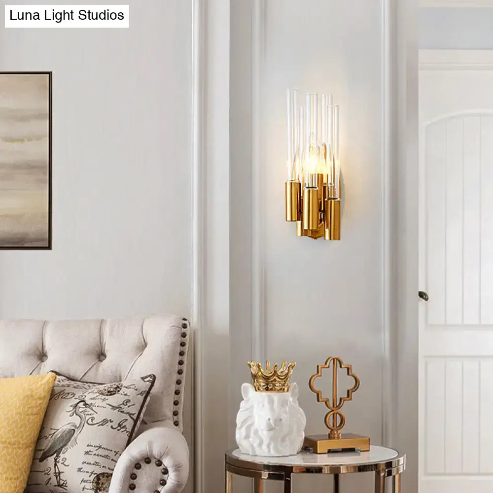 Gold-toned nordic wall lamp with clear glass cylinders and warm glowing bulbs for living room gold tube lighting