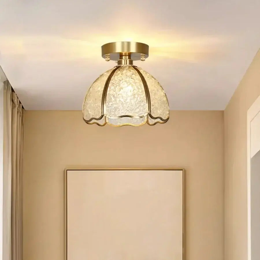 A gold-toned crystal ceiling light with a textured translucent glass shade shaped like a flower for bedroom use