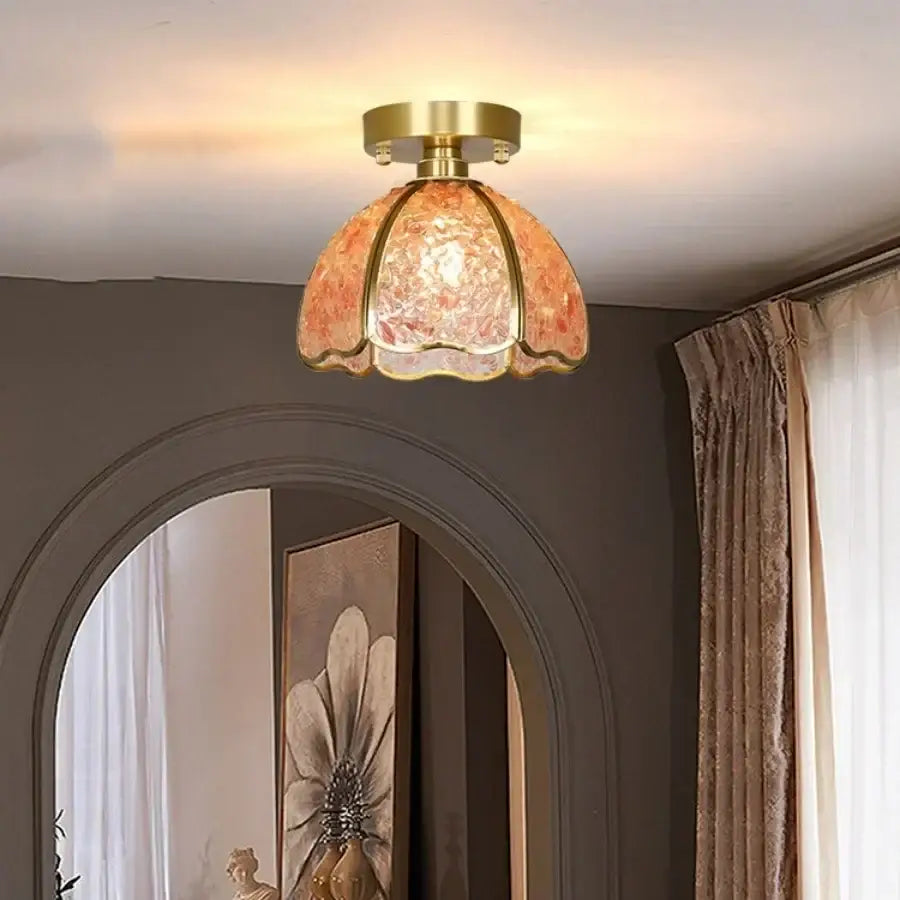 A warm-toned amber glass crystal ceiling light with brass frame and scalloped edges for bedroom decor