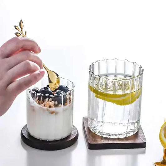 Gold leaf spoon with slender handle holding blueberries and granola in a nordic heat resistant glass ripple cup