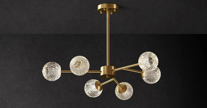Gold-toned nordic pendant chandelier with six clear textured glass globe shades for dining room indoor lighting