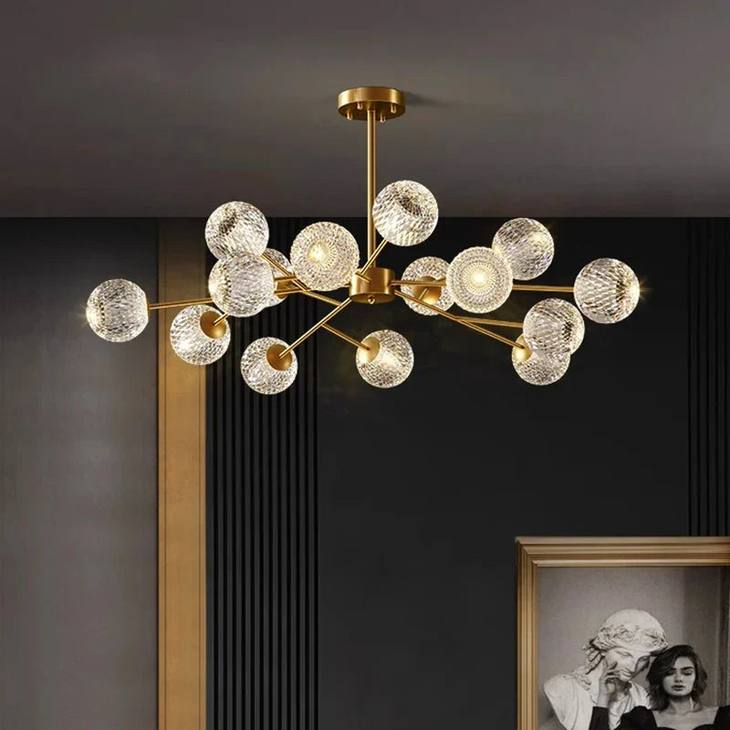 Gold-toned metal pendant lamp with clear textured glass spheres in a modern branching design for dining room lighting