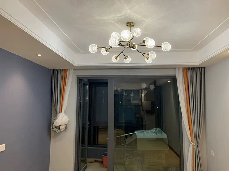 Modern chandelier with brass-colored metal arms and frosted glass globe bulbs for nordic dining room lighting