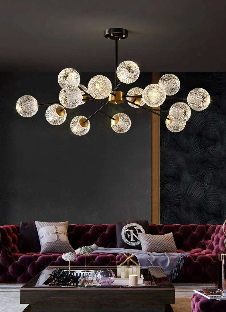 A modern black and gold metal frame pendant lamp with clear textured glass spheres for indoor dining room lighting