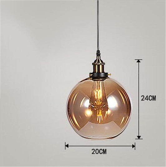 Amber glass globe pendant light with black metal accents and a vintage edison bulb.