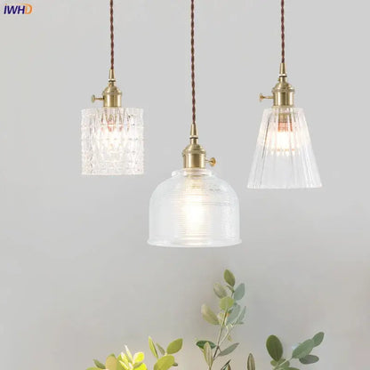 Three nordic japan style pendant lights with brass fixtures and textured clear glass shades for dining room lighting