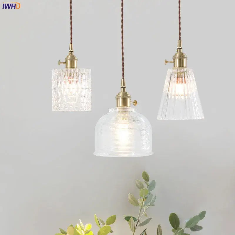 Three nordic japan style pendant lights with brass fixtures and textured clear glass shades for dining room lighting