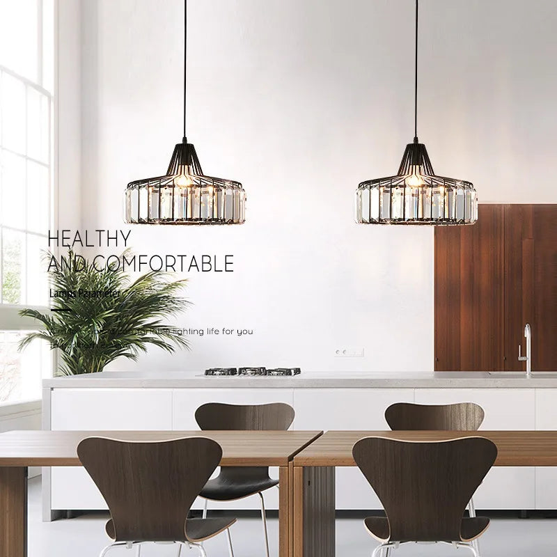 Two black-framed nordic led crystal pendant lamps with clear glass accents hang above a dining table chandelier