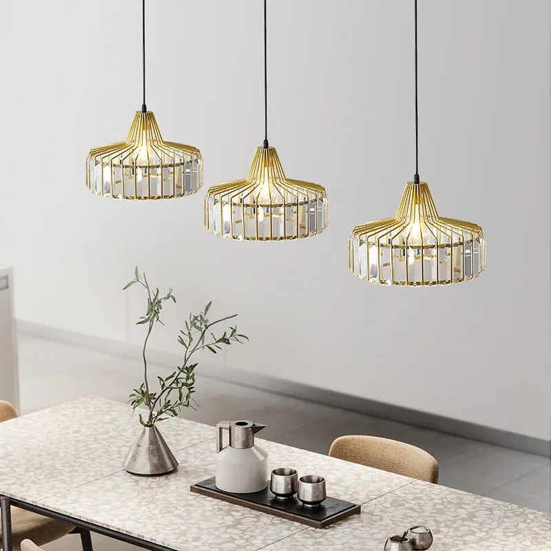 Three elegant gold-toned nordic led crystal pendant lamps with clear accents hanging above a dining table