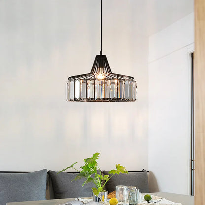 Black metal nordic LED crystal pendant lamp with clear glass accents hanging above a dining room table