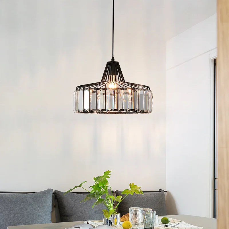 Black metal nordic LED crystal pendant lamp with clear glass accents hanging above a dining room table