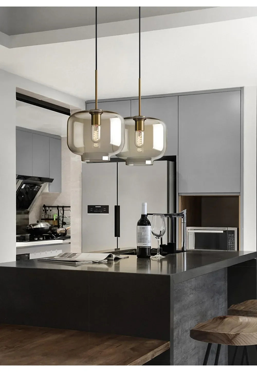 Two nordic led glass pendant lights with smoked glass shades and brass accents hang above a dark dining room island