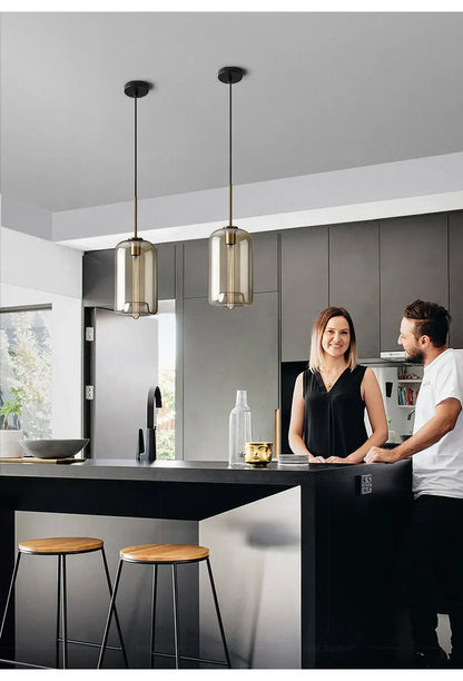 Two sleek nordic led glass pendant lights with smoked glass and brass finish hang in dining room setting