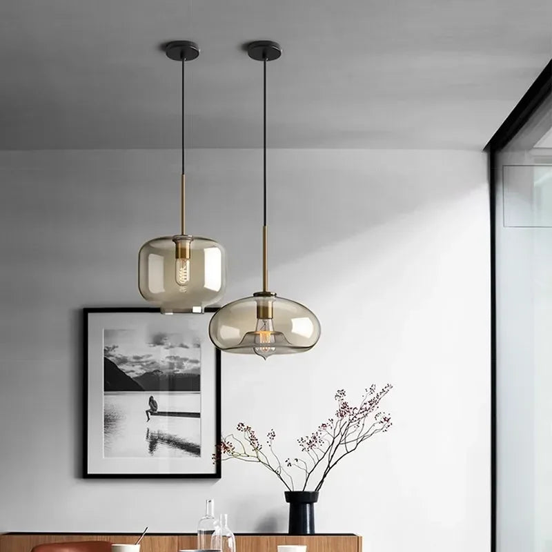 Two modern nordic led glass pendant lights with smoked glass shades and brass accents for dining room use