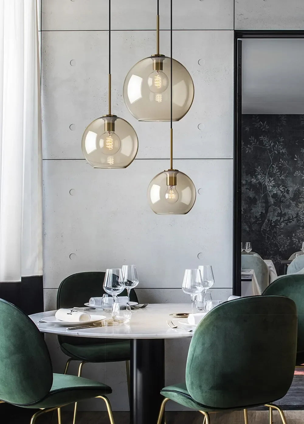 Three spherical nordic led glass pendant lights with brass accents hang above a dining room table