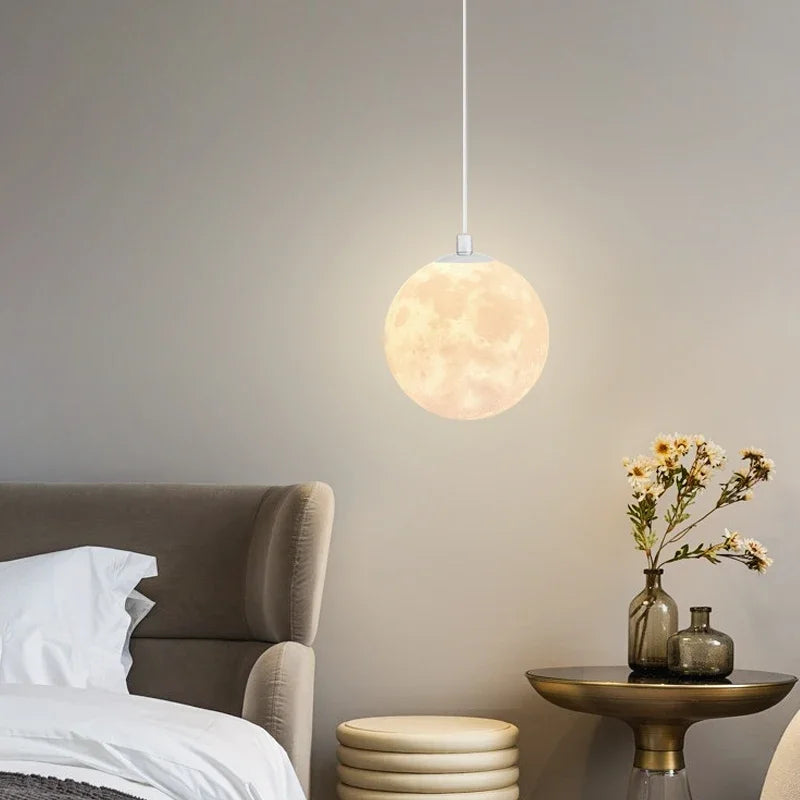 A warm glowing spherical nordic led moon pendant light with detailed moon surface for dining room kitchen decor