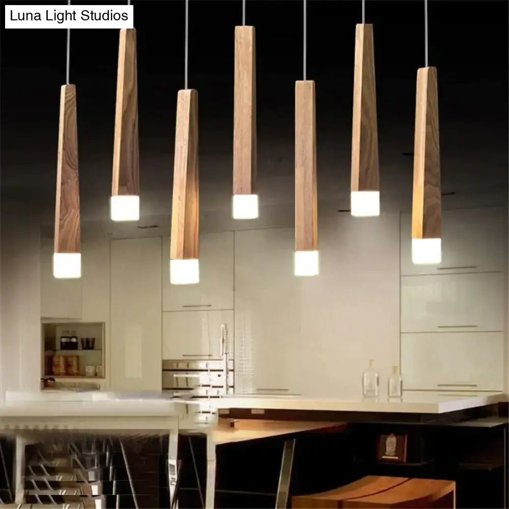 Five nordic minimalist wood pendant lamps with slender wooden bodies and warm white bases hanging in a dining room