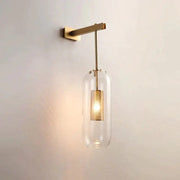 A nordic modern decor brass and glass wall lamp with a clear glass lampshade and perforated gold-toned shade for bedroom