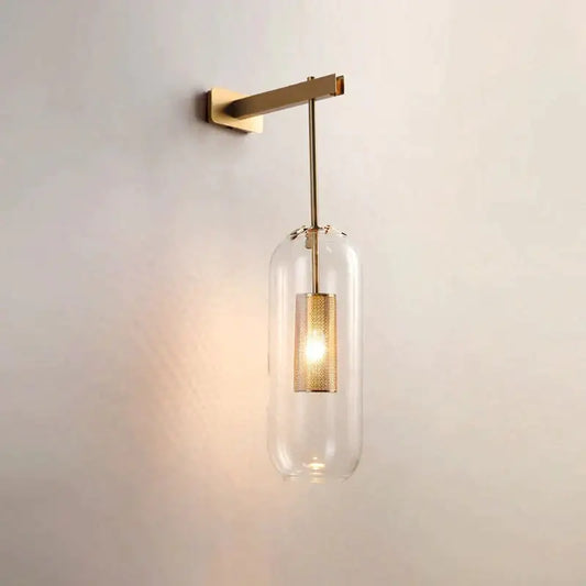 A nordic modern decor brass and glass wall lamp with a clear glass lampshade and perforated gold-toned shade for bedroom