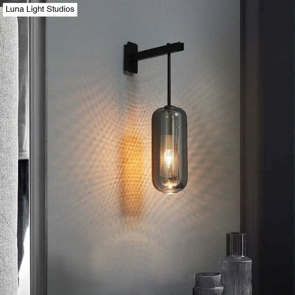 A sleek black metal wall sconce with a cylindrical smoked glass lampshade in nordic modern decor style