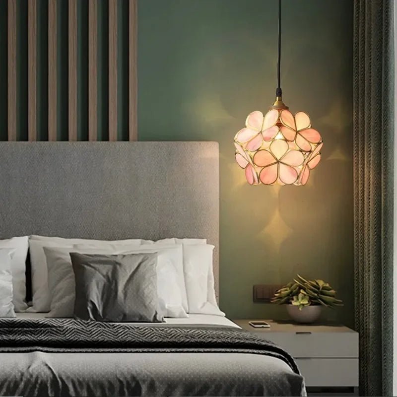 A delicate pink and peach Nordic modern petal acrylic pendant lamp with floral design hanging above the bed