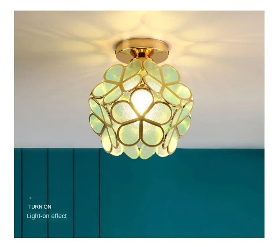 A nordic modern golden floral ceiling light with greenish translucent acrylic panels in a spherical pendant design