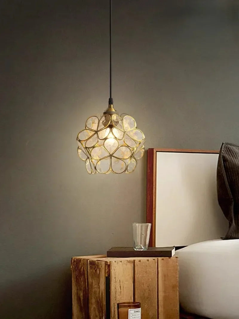 A warm brass-toned nordic modern petal acrylic pendant lamp with translucent flower-like glass panels for bedroom lighting