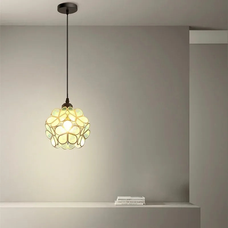 A nordic modern petal acrylic pendant lamp with greenish-yellow glass floral design and warm glow, suspended by dark chain