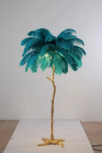 A tall feather floor lamp with a golden tree trunk base and teal ostrich feathers for living room decor