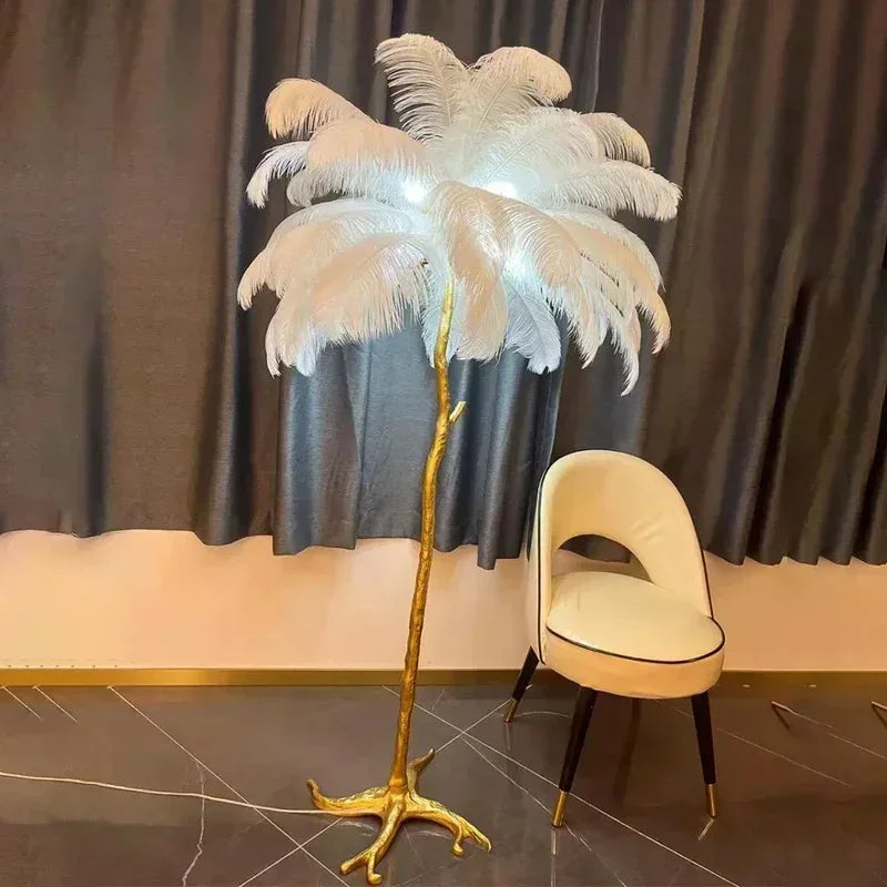 A tall elegant floor lamp with a golden metallic base and white soft ostrich feathers for living room decor