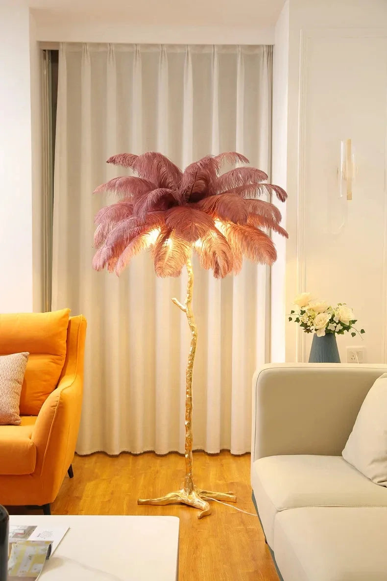 A tall elegant feather floor lamp with a golden tree trunk base and pink ostrich feathers for living room decor