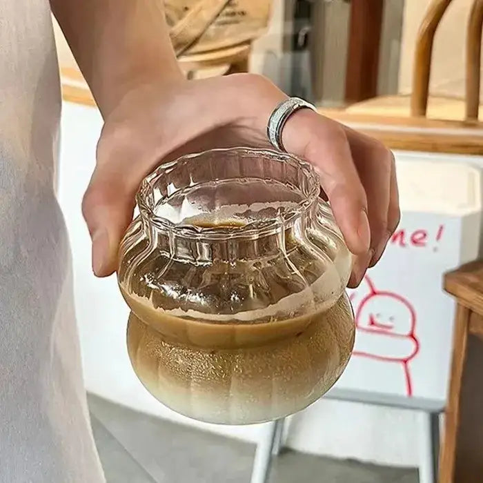 A clear ribbed glass cocktail cup with scalloped rim holds iced coffee in the nordic pink decorbites glass cocktail set