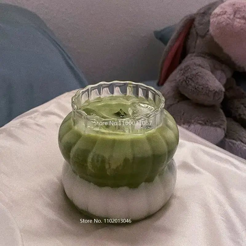 A green and white layered candle in a clear glass jar with fluted edges for decorbites glass cocktail cups set