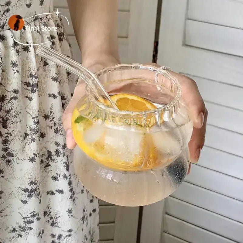 Clear glass pitcher with scalloped rim and handles filled with lemon water featuring glass cocktail cups set decorbites