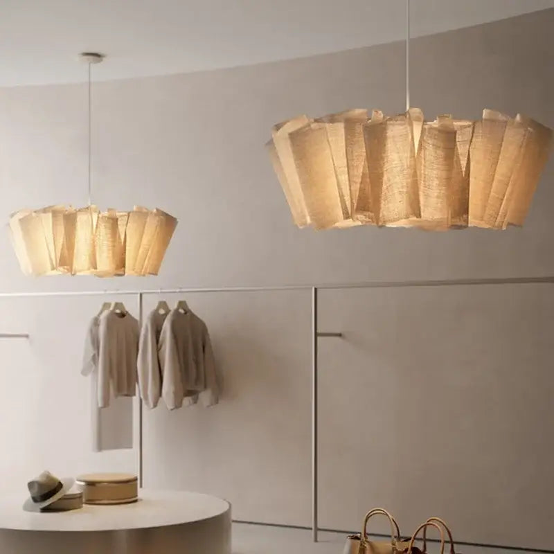 Two beige pleated paper pendant lights in creamy white fabric hang from ceiling for dining room lighting