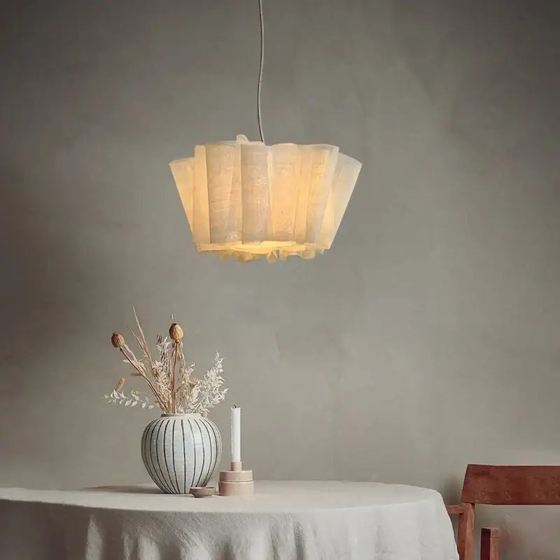 A warm pendant light with a creamy white fabric petal-like shade ideal for dining room illumination