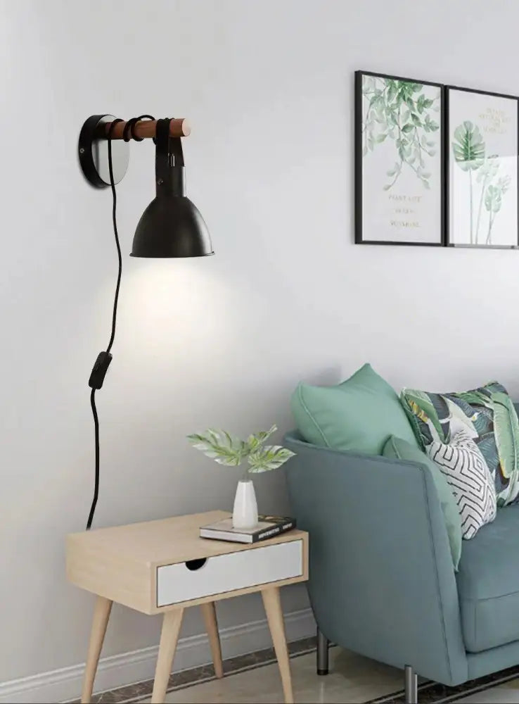 Black metal wall sconce with wooden accent arm and black finish featuring algunda plug for easy installation