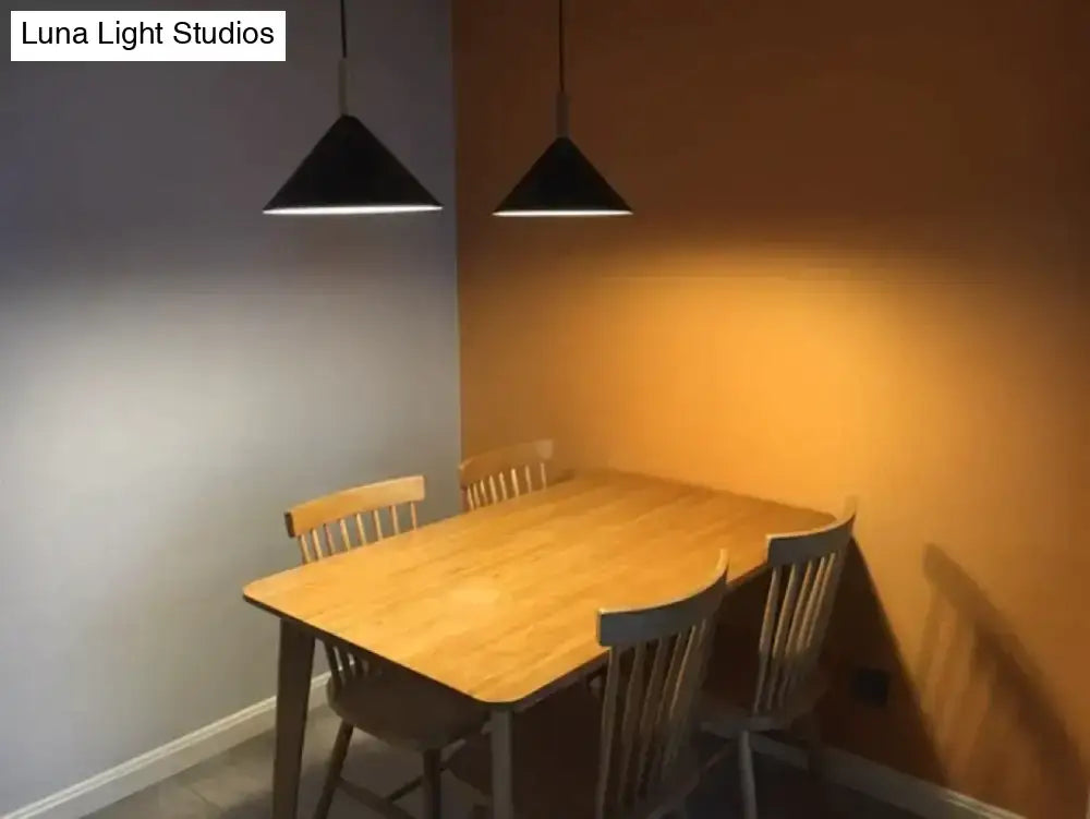 Black conical nordic simple kitchen pendant light with sleek metal fixtures hanging above a wooden dining table