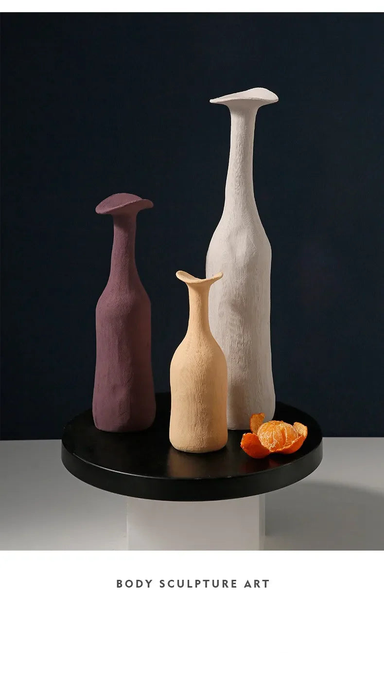 Three slender modern vases in muted purple beige and white with textured surfaces on a black circular base for nordic decor