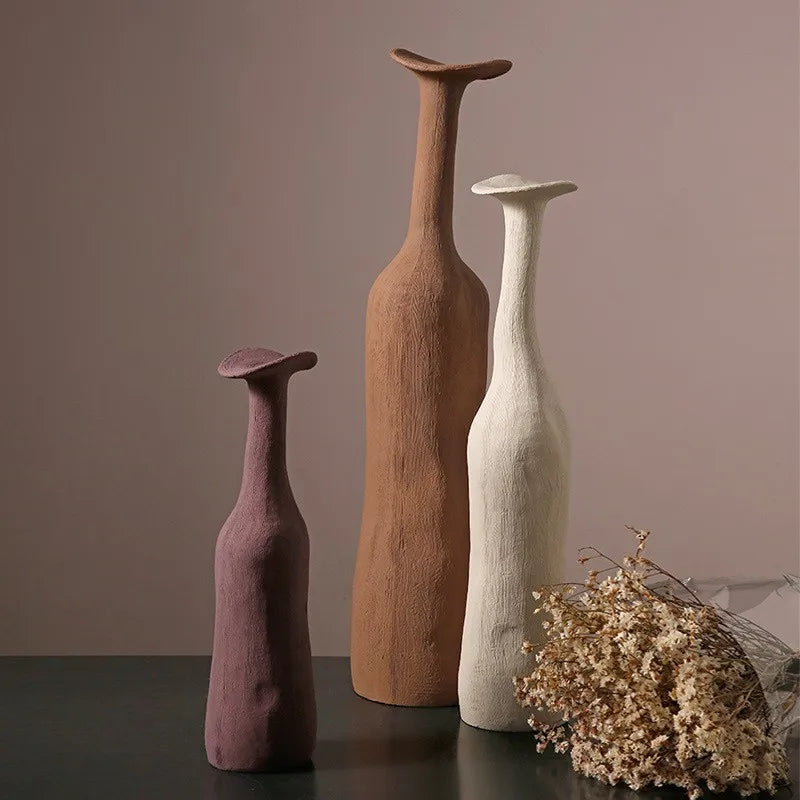 Three sculptural ceramic vases in morandi colors purple terracotta and off-white with textured surfaces and flared tops for modern home decoration
