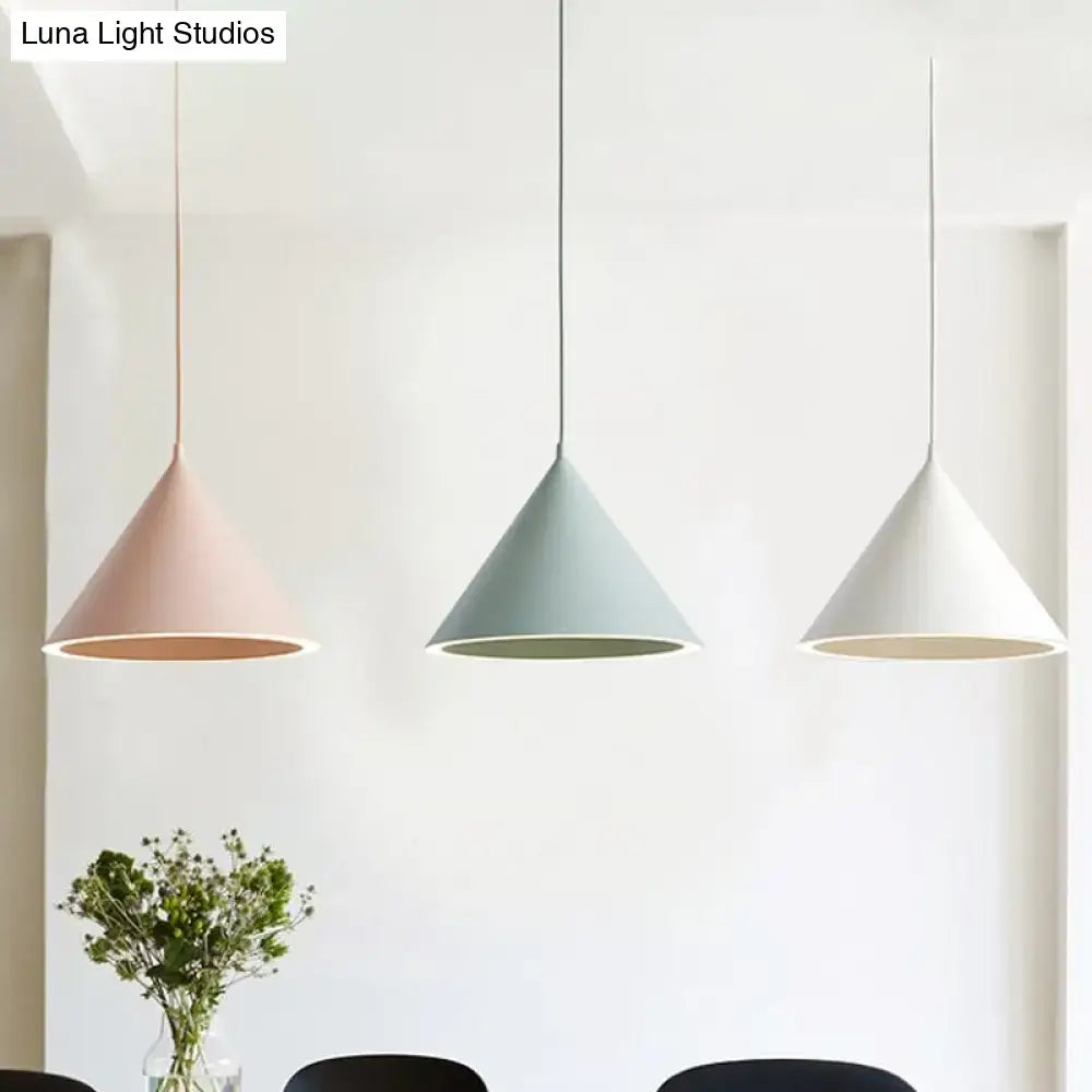 Three modern cone-shaped nordic stylish pendant lights in soft pink, muted green, and white hanging lamp over table