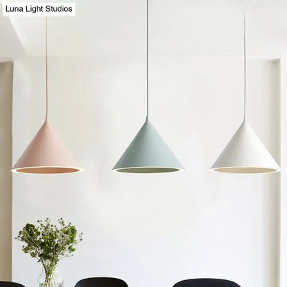 Three modern cone-shaped nordic stylish pendant lights in soft pink, muted green, and white hanging lamp over table