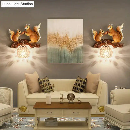 Pair of bronze-colored vintage style resin squirrel wall lamps with detailed fur mounted on dark wood branches above sofa