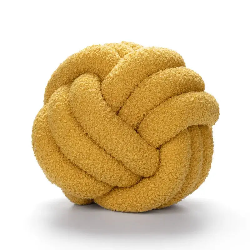 A plush mustard-yellow decorbites boucle knotted circle throw pillow made of soft textured fabric for bedroom decor