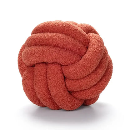 A coral-colored plush knotted circle throw pillow made of soft boucle knotted circle fabric for bedroom decor