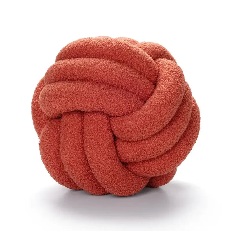 A coral-colored plush knotted circle throw pillow made of soft boucle knotted circle fabric for bedroom decor